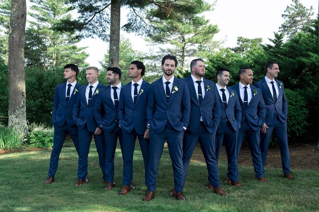 Groom and groomsmen wearing navy blue suits posing outdoors for a wedding portrait in Massachusetts